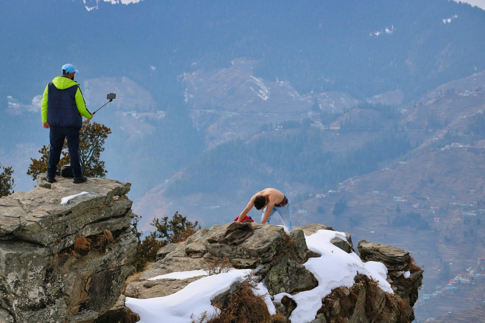 a man standing on top of a mountain next to snow covered rocks